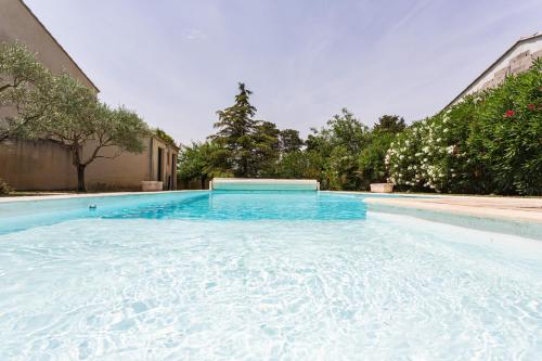 une piscine remplie d'eau bleue à côté d'un bâtiment dans l'établissement Le Mas du Château en Provence, au Pontet