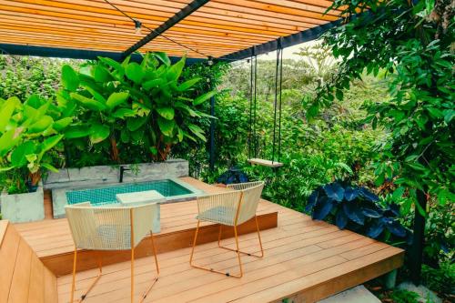 a patio with a hot tub and two chairs on a wooden deck at Ecohotel Monte Tierra Habitaciones y Glamping in Filandia