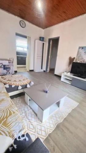 un salon avec une table et un réfrigérateur dans l'établissement Le refuge boisé, à Mimizan