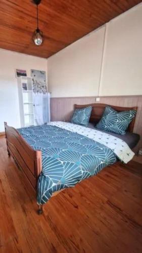 un grand lit dans une chambre avec un plancher en bois dans l'établissement Le refuge boisé, à Mimizan