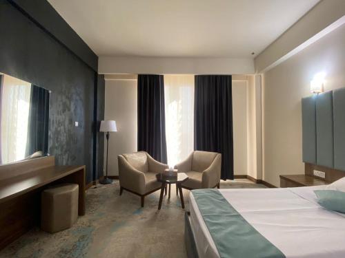 Cette chambre comprend un lit, un bureau et des chaises. dans l'établissement Khawarnaq Palace Hotel, à An Najaf