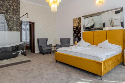 a bedroom with a bed and two chairs and a mirror at La Maison de Caroline in Alba Iulia