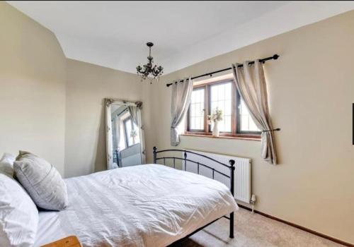 a bedroom with a bed and two windows at Home by the Sea in Clacton-on-Sea