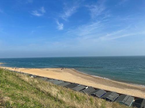 a beach with a row of chairs and the ocean at Home by the Sea in Clacton-on-Sea
