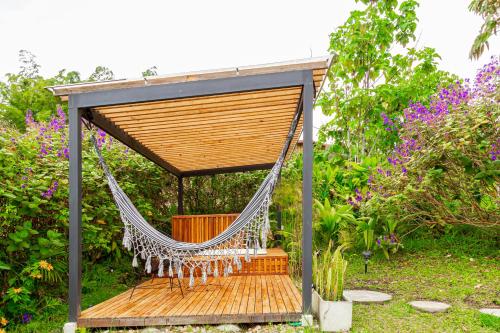 a hammock swing in a garden with flowers at Ecohotel Monte Tierra Habitaciones y Glamping in Filandia