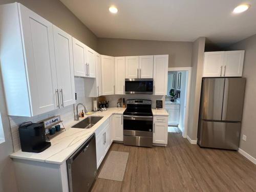 Una cocina con gabinetes blancos y electrodomésticos de acero inoxidable. en Chic & intimate 2 bedroom, en Brighton
