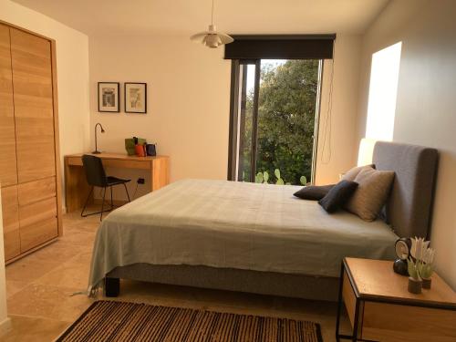 Schlafzimmer mit einem Bett, einem Fenster und einem Schreibtisch in der Unterkunft Villa Fogata à l'Ile Rousse vue mer exceptionnelle in LʼÎle-Rousse