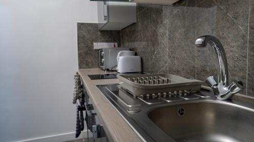 um balcão de cozinha com um lavatório e uma mesa de mistura em VR Apartments em Glasgow