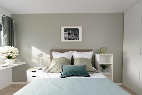a white bedroom with a bed with a green pillow at HOTEL LES PORTES DE PARIS in Ivry-sur-Seine