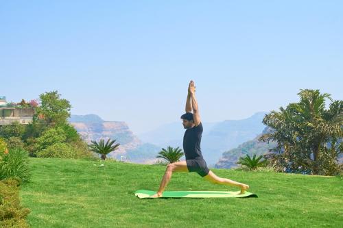 a man doing a yoga pose on a surfboard at Ikshana Resort and Spa, Khandala in Lonavala