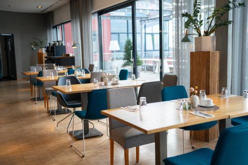 a restaurant with wooden tables and blue chairs at Hotel Soho in Landau in der Pfalz