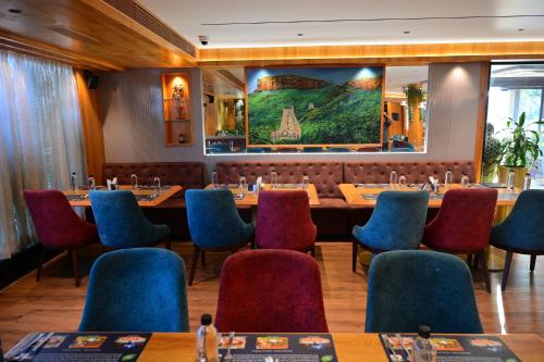 a restaurant with a long table and chairs at Hotel Golden Riviera in Mysore