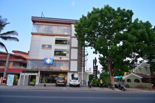 a building on the corner of a street with a tree at Hotel Golden Riviera in Mysore