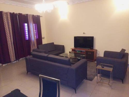 uma sala de estar com dois sofás e uma televisão em Comfort Zone Apartment em Iaundé