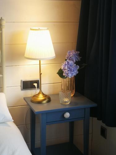 a table with a lamp and a vase of purple flowers on it at La casa de Sara in Novés de Segre