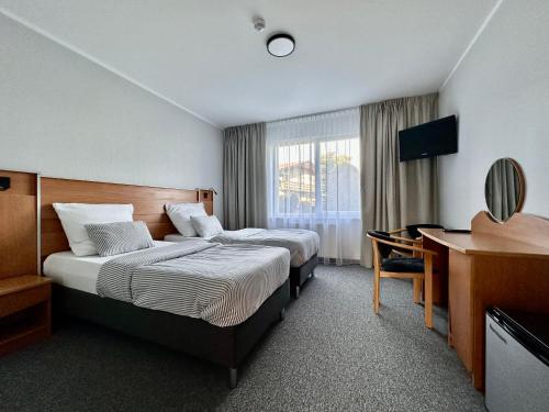 una camera d'albergo con 2 letti e una scrivania di KARAT a Malbork