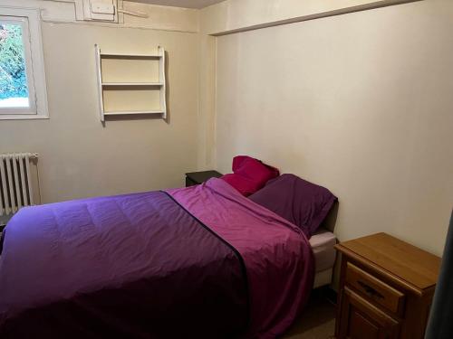- une chambre avec un lit doté de draps violets et une fenêtre dans l'établissement Studio dans maison avec jardin, à Rueil-Malmaison