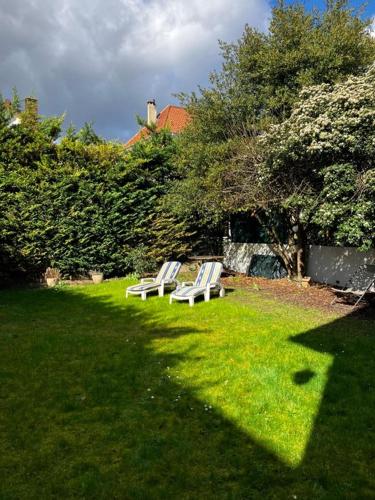 2 chaises longues blanches assises dans l'herbe dans l'établissement Studio dans maison avec jardin, à Rueil-Malmaison