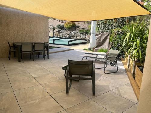 a patio with chairs and tables and a yellow umbrella at Studio cosy avec terrasse et accès piscine in Aurec-sur-Loire
