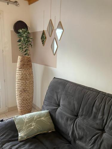 a black leather couch in a living room with a plant at Gîte des champs fondus in Picauville