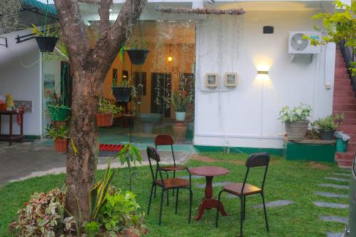 eine Terrasse mit Stühlen, einem Tisch und einem Baum in der Unterkunft Jaya Villa in Negombo