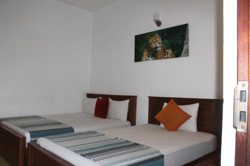 a room with two beds and a picture on the wall at UD Garden Hotel in Kataragama