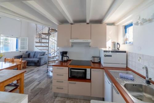 a kitchen with white cabinets and a living room at ILIOS in Perlopsimades