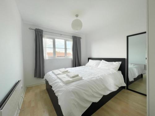 a bedroom with a large white bed with a mirror at Colliers Wood 1 Bed South London Short Stay in Mitcham