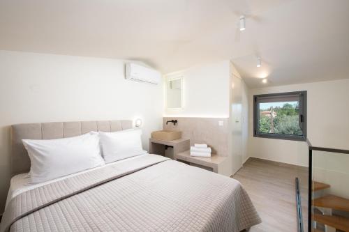 una camera con un letto bianco e una finestra di Theros Serenity Suites a Olympiada