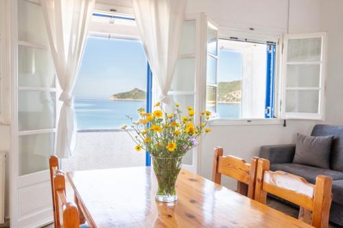a vase of flowers on a wooden table in a living room with a view at ILIOS in Perlopsimades