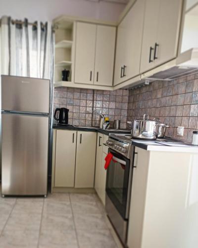 a kitchen with white cabinets and a stainless steel refrigerator at Athani Summer House (Apartments 01 - 02) in Athanion