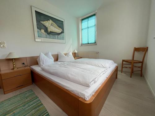 1 dormitorio con 1 cama, 1 silla y 1 ventana en Apartmenthaus Aurum, en Ahlbeck