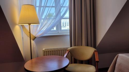 a room with a table and a chair and a window at Hotel Maxim Kwidzyn in Kwidzyn