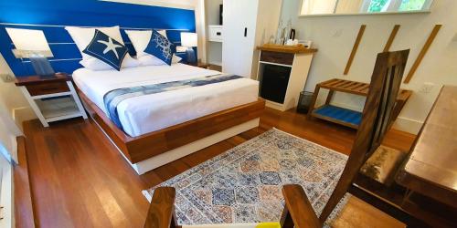 a bedroom with a large bed with a blue headboard at The Fulhadhoo Beach Cottage in Fulhadhoo