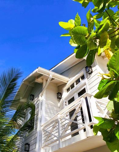 a white building with green trees in front of it at The Fulhadhoo Beach Cottage in Fulhadhoo