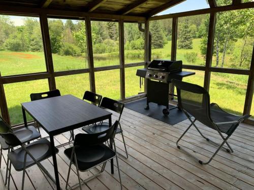 porche cubierto con mesa, sillas y parrilla en Tranquil private get away cottage in the woods, 