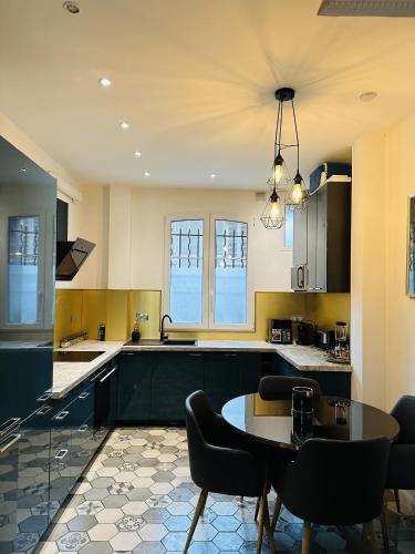 une cuisine avec des armoires noires, une table et des chaises dans l'établissement Oasis urbaine à 10 min de Paris, à Argenteuil