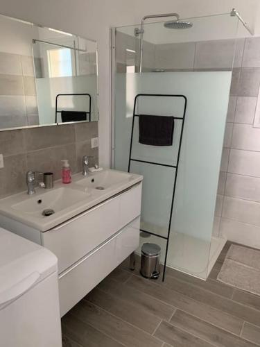 une salle de bain blanche avec un lavabo et un miroir dans l'établissement Gîte du Planas, à Bollène