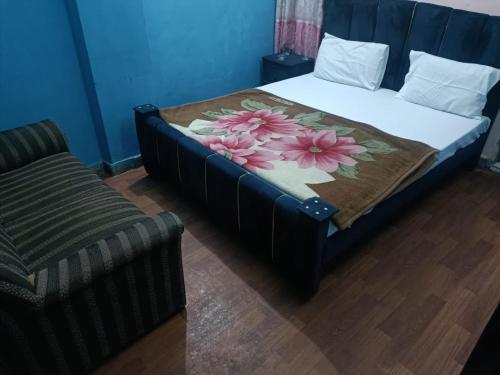 a bedroom with a bed with a flower blanket and a couch at Hotel Lahore City in Lahore