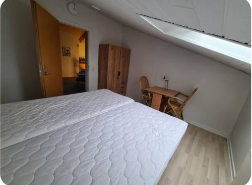 a white bed in a room with a table at Værelse til leje 4 in Hørve