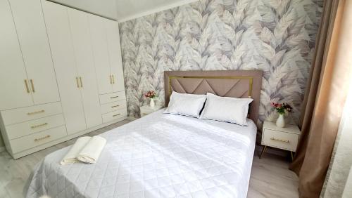 um quarto com uma cama com lençóis brancos e flores em 3х-ком Люкс в центре Шымкента Проспект Б Момышулы 4 em Shymkent