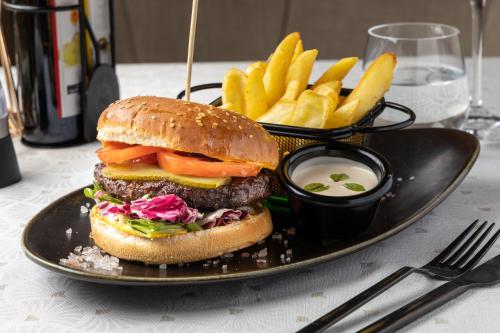 a black plate with a hamburger and fries and dip at La Maison de Caroline in Alba Iulia