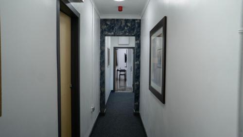 a hallway with white walls and a long hallway with paintings at VR Apartments in Glasgow