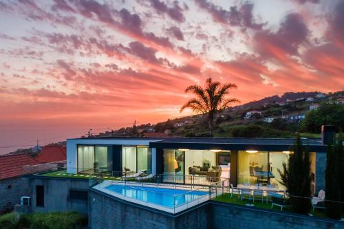 a house with a swimming pool at sunset at Luxury Ocean View Villa I Swimming pool I Vincents Place in Estreito da Calheta