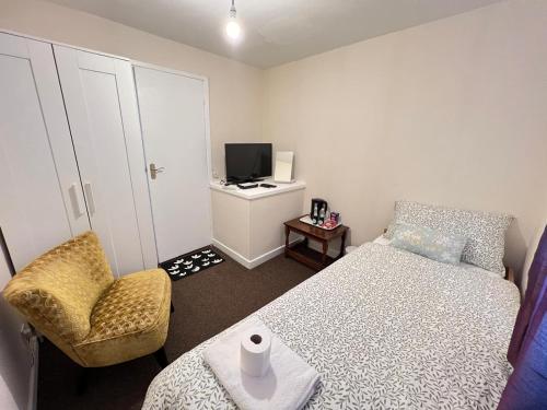 a bedroom with a bed and a chair and a television at Residence Solitaire in Woodley