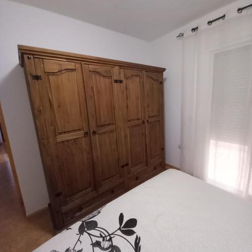 a bedroom with a bed and a wooden cabinet at Apartamento completo NERUDA in Carboneras