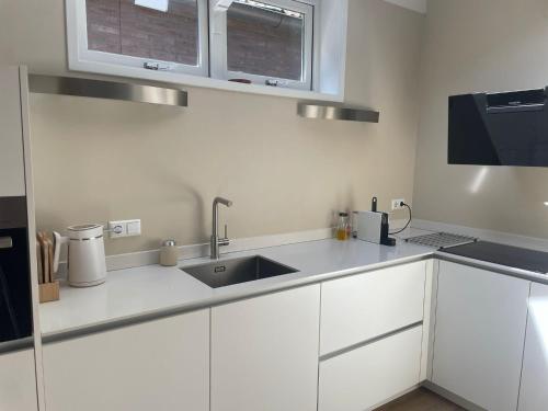 a kitchen with white cabinets and a sink at Huisje Hendrik in Baarn