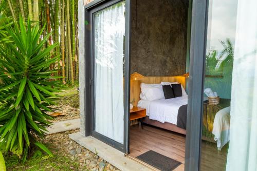 a bedroom with a bed and a sliding glass door at Ecohotel Monte Tierra Habitaciones y Glamping in Filandia