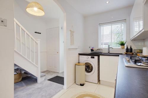 a white kitchen with a washer and dryer in it at Seapoint- Boho Coastal Retreat near Sandbanks! in Poole