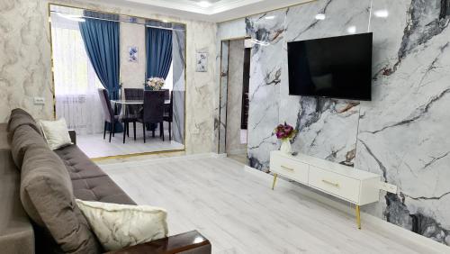 uma sala de estar com televisão numa parede de mármore em 3х-ком Люкс в центре Шымкента Проспект Б Момышулы 4 em Shymkent